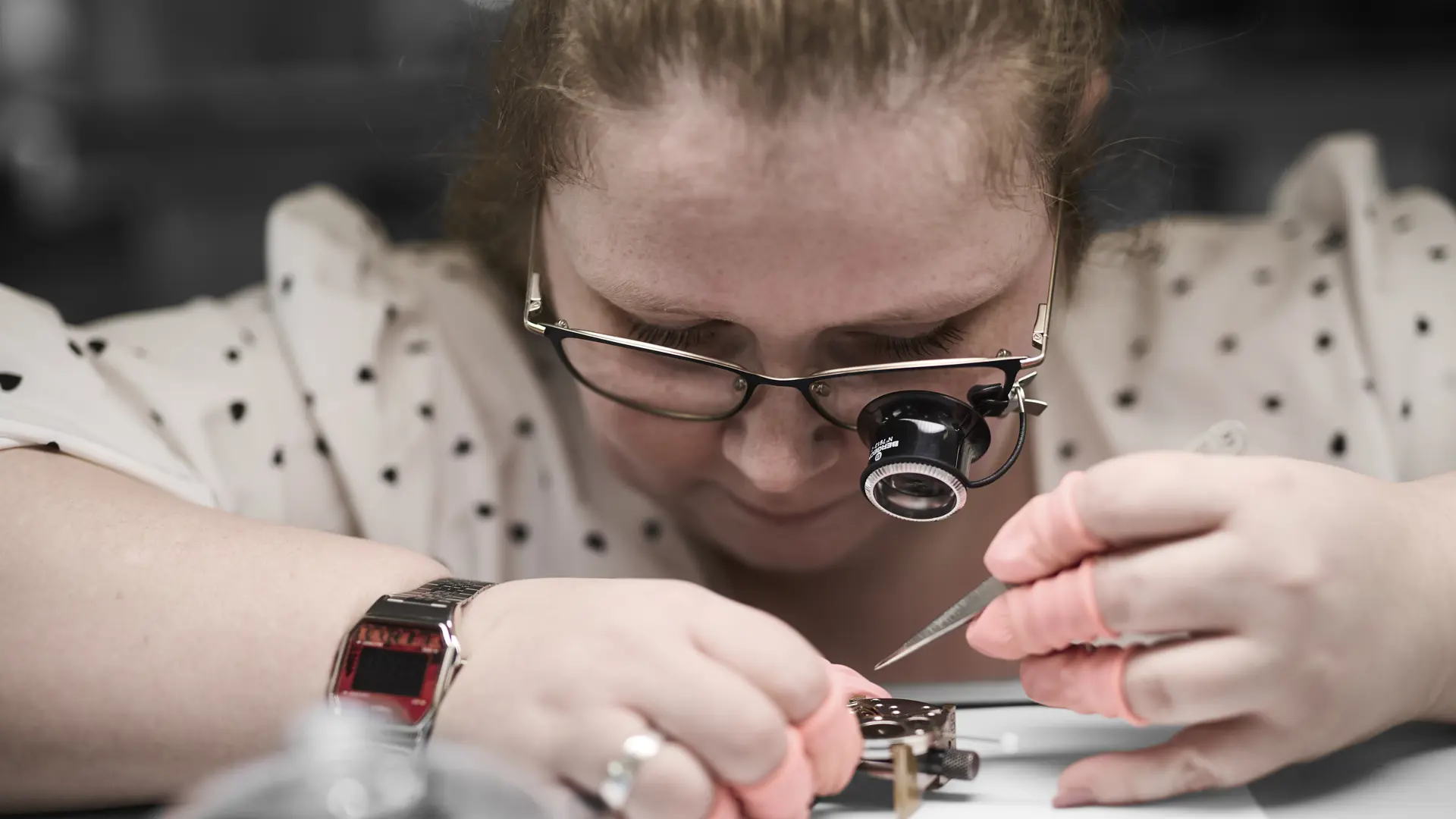 Urmager med lup arbejder med pincet på urværk